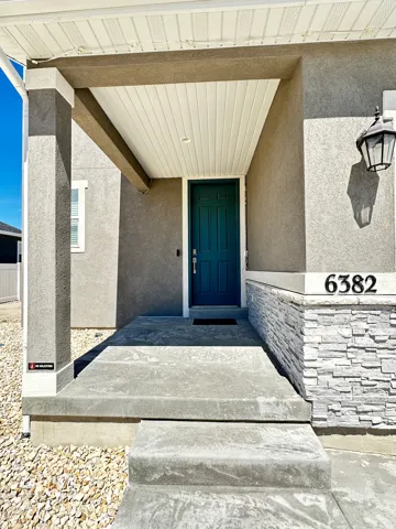 Covered entry with a teal paneled door, complemented by a decorative outdoor lantern
