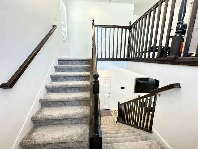 Multi-level staircase featuring carpeted treads and dark wood-finish handrails and balusters