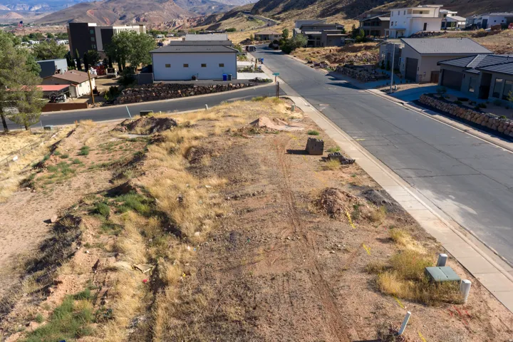 Expansive undeveloped lot featuring street frontage, established curb and sidewalk, and visible utility boxes