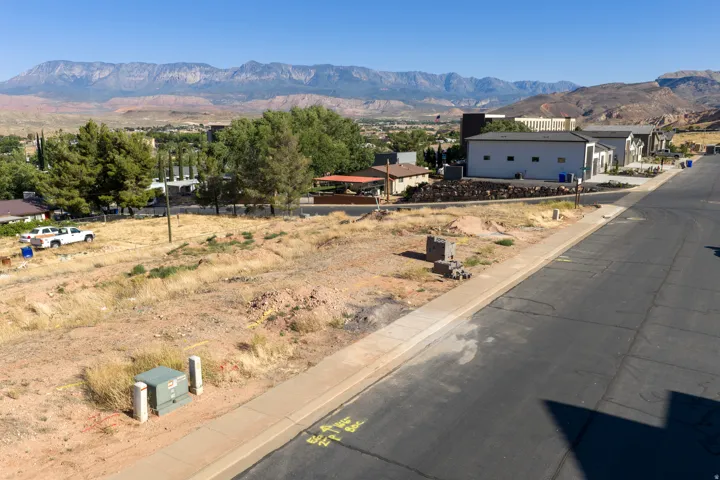 Expansive vacant land featuring a paved street and concrete sidewalk