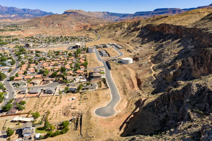 Aerial perspective showcasing a residential development nestled against a natural rock formation backdrop, with a distinct cul-de-sac