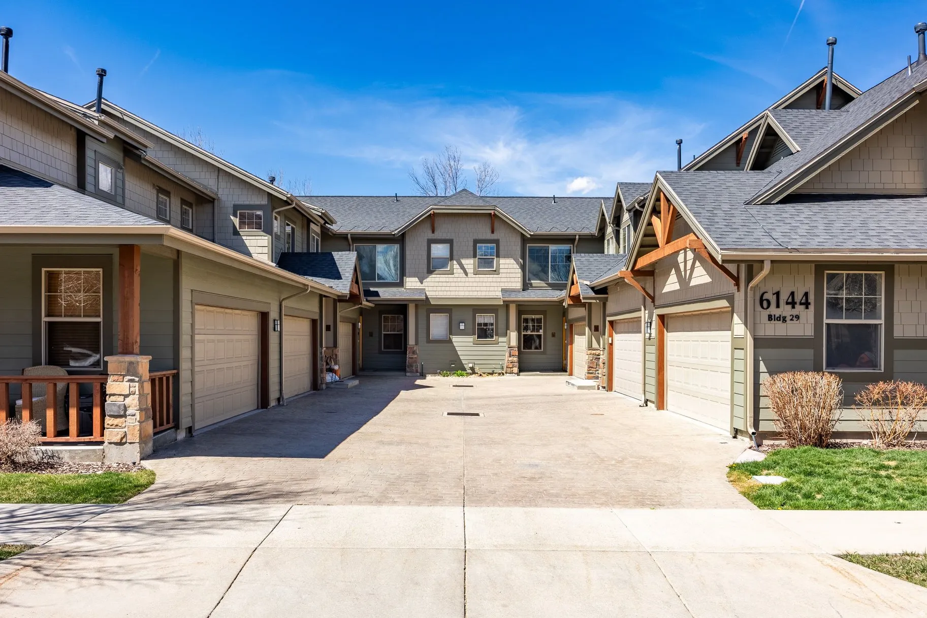 Modern multi-unit development featuring individual attached garages, pitched shingle roofs, and board-and-batten siding
