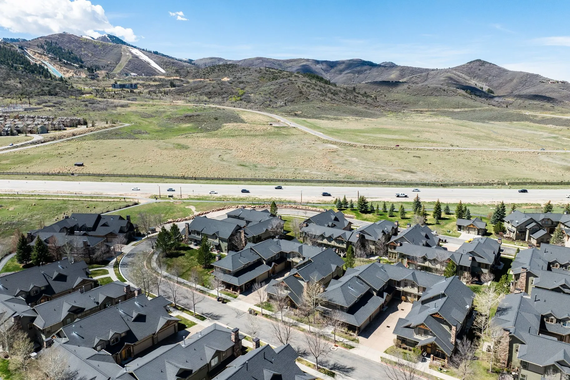 Residential development featuring a mountain backdrop, paved roadways, and surrounding natural landscapes