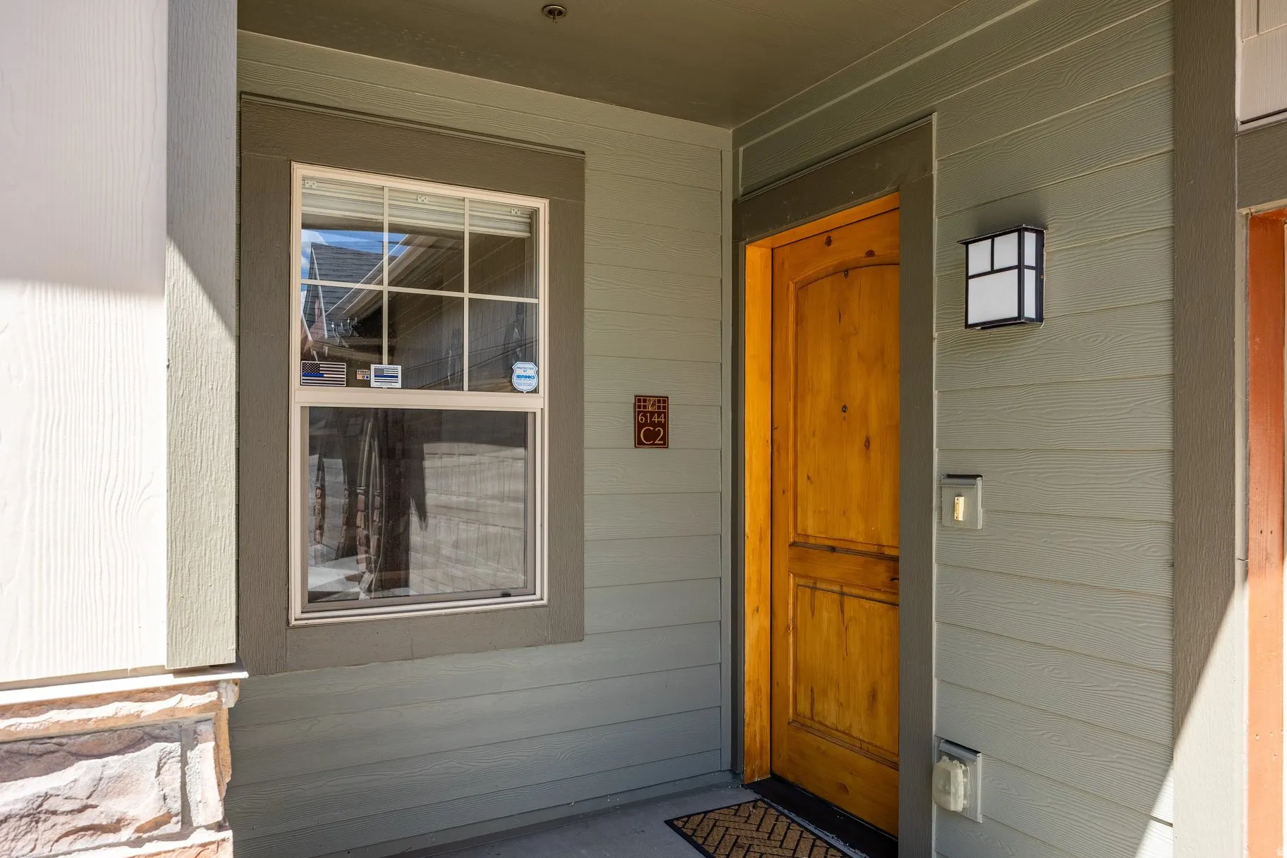 Entryway featuring a wood-panel door, exterior wall lantern, and a window with white grid panes