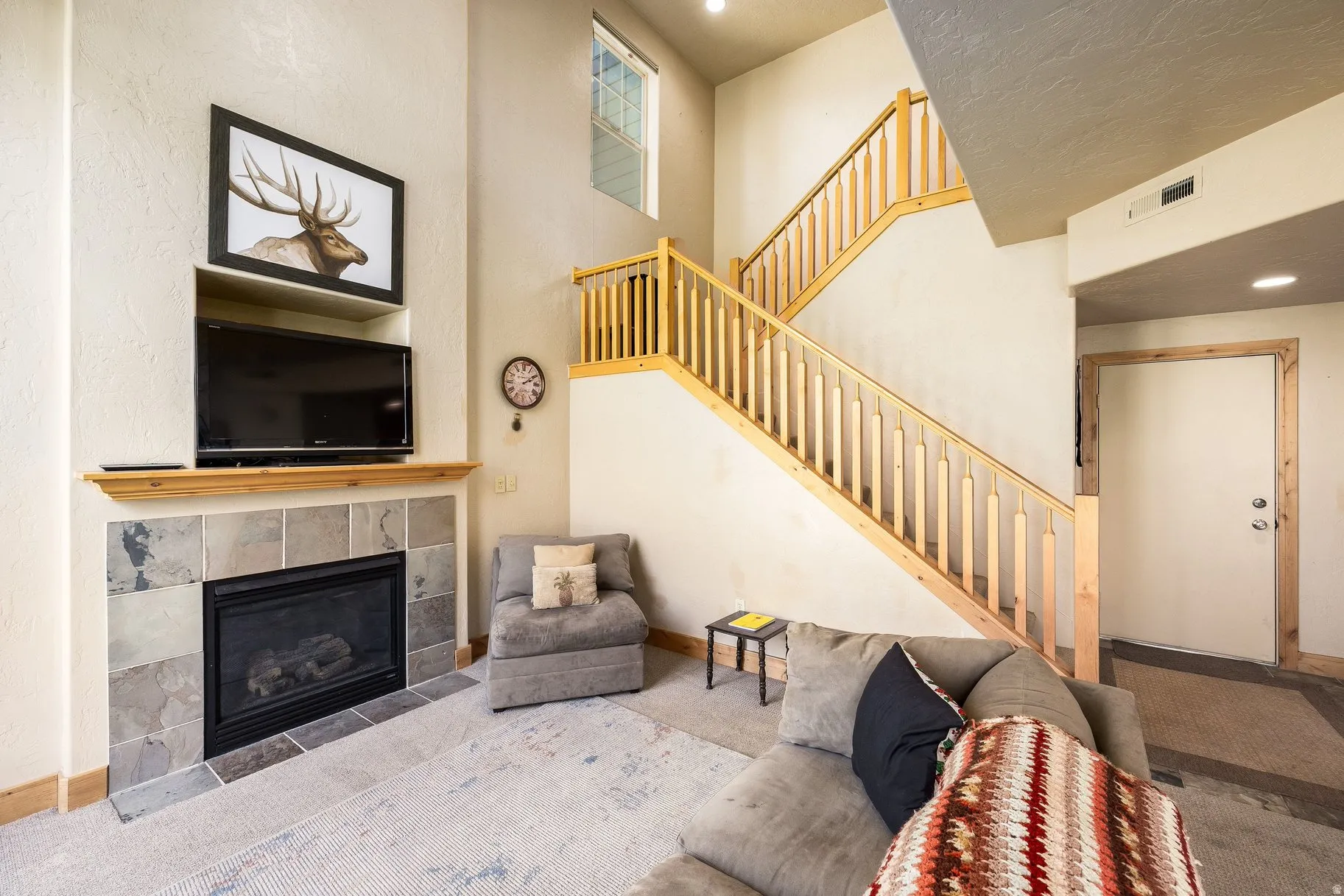 Living area featuring a floor-to-ceiling fireplace with a tile surround and wood mantel
