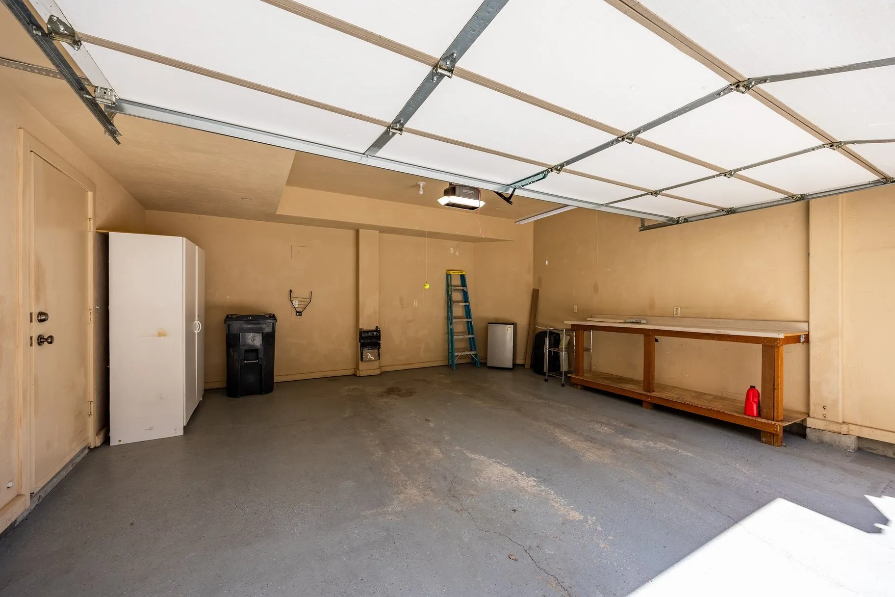 Spacious garage featuring a concrete floor, overhead lighting, and an overhead garage door
