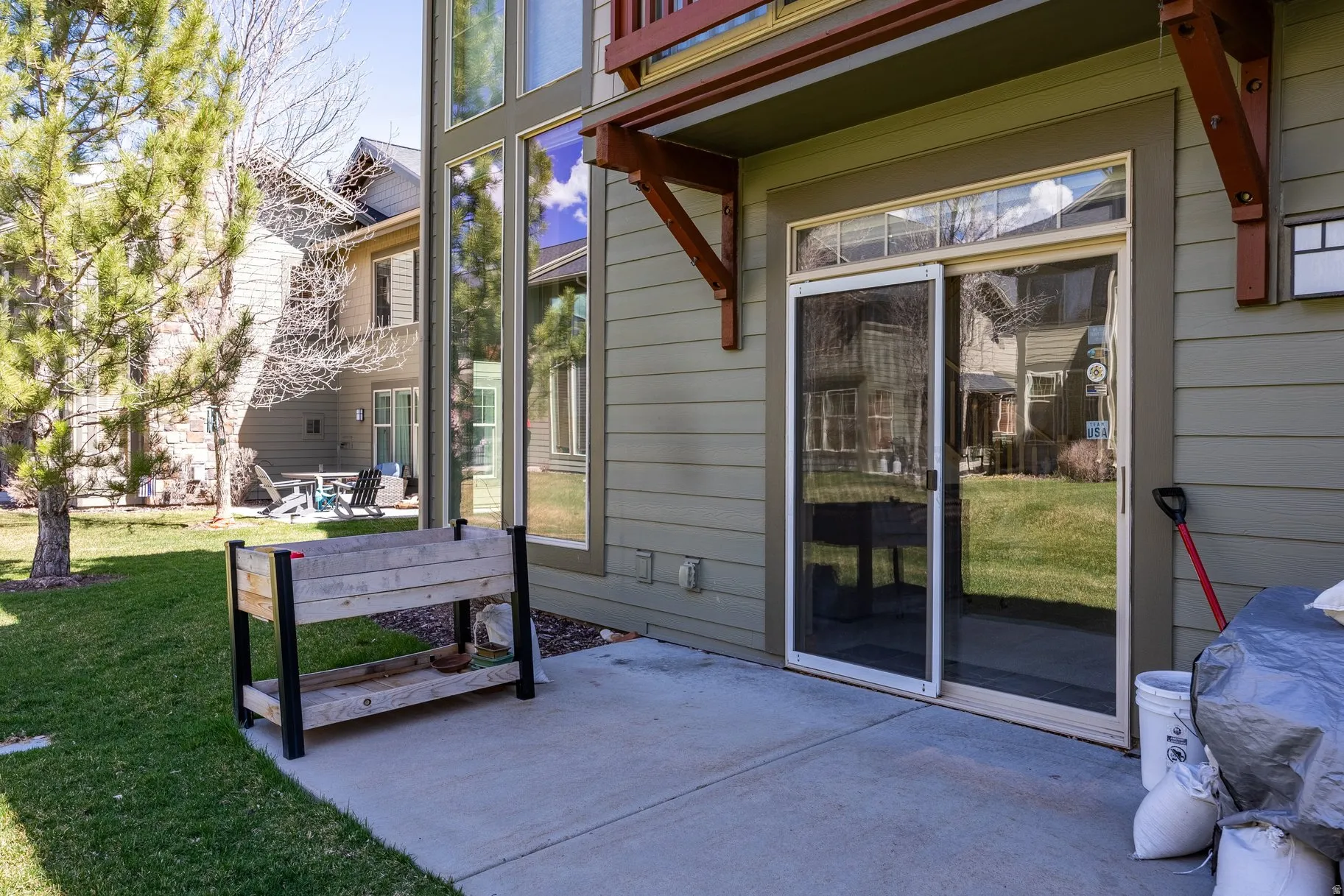Private patio with sliding glass door access to the interior, featuring a concrete surface and surrounding green lawn