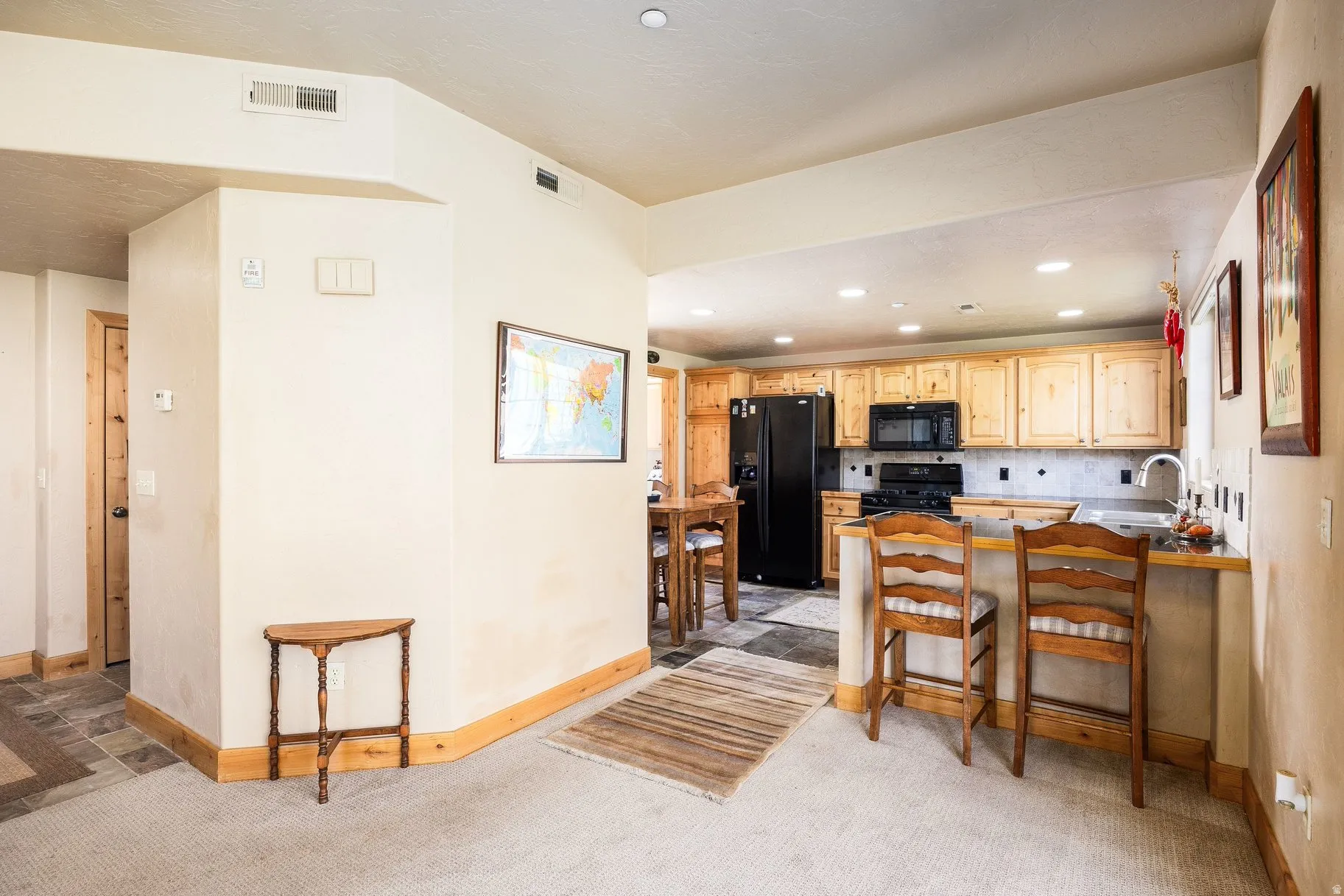 Kitchen area featuring light wood cabinetry, black appliances, a double basin sink, and recessed lighting