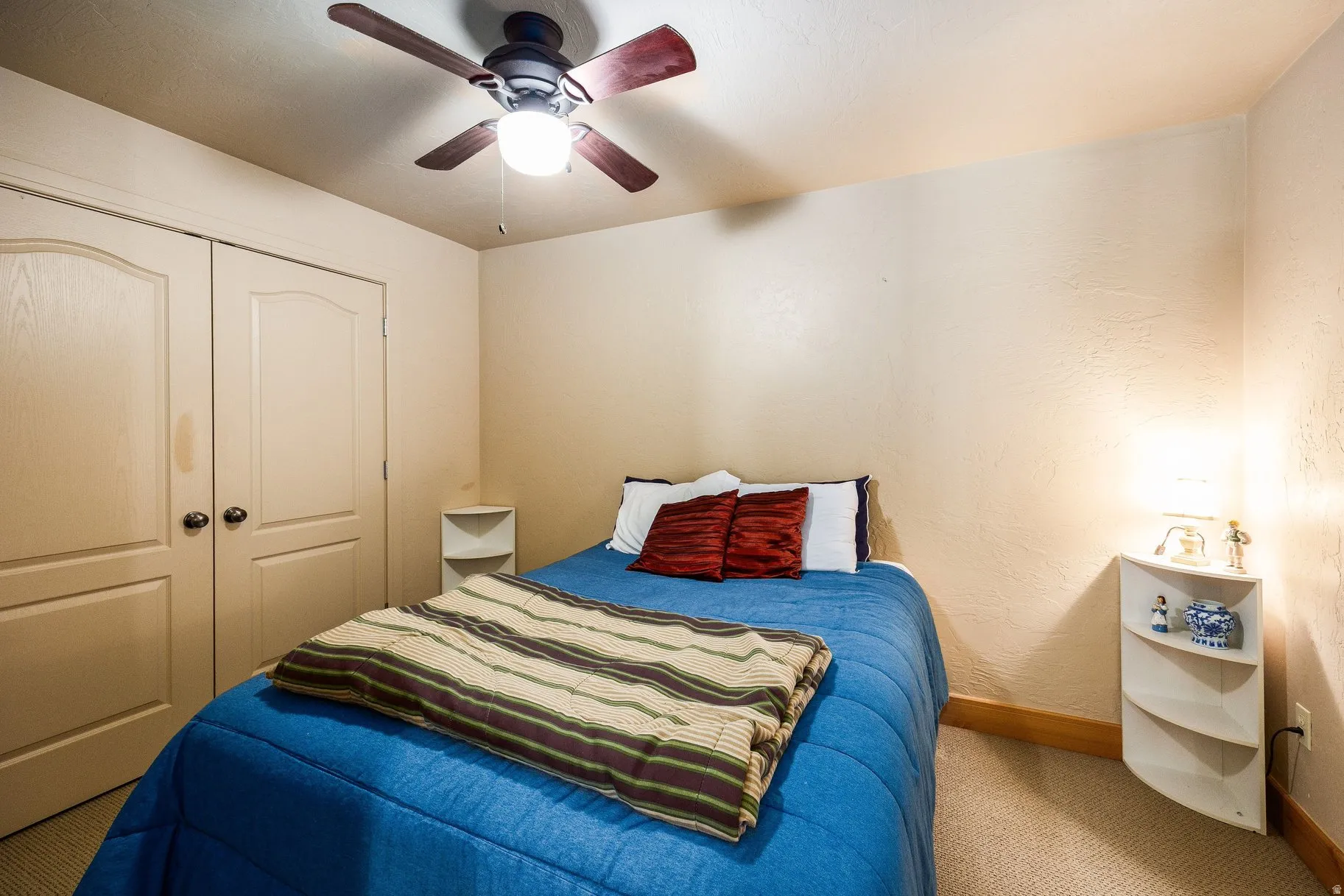 Bedroom featuring neutral wall tones, carpet flooring, a ceiling fan with integrated lighting, and double bi-fold closet doors