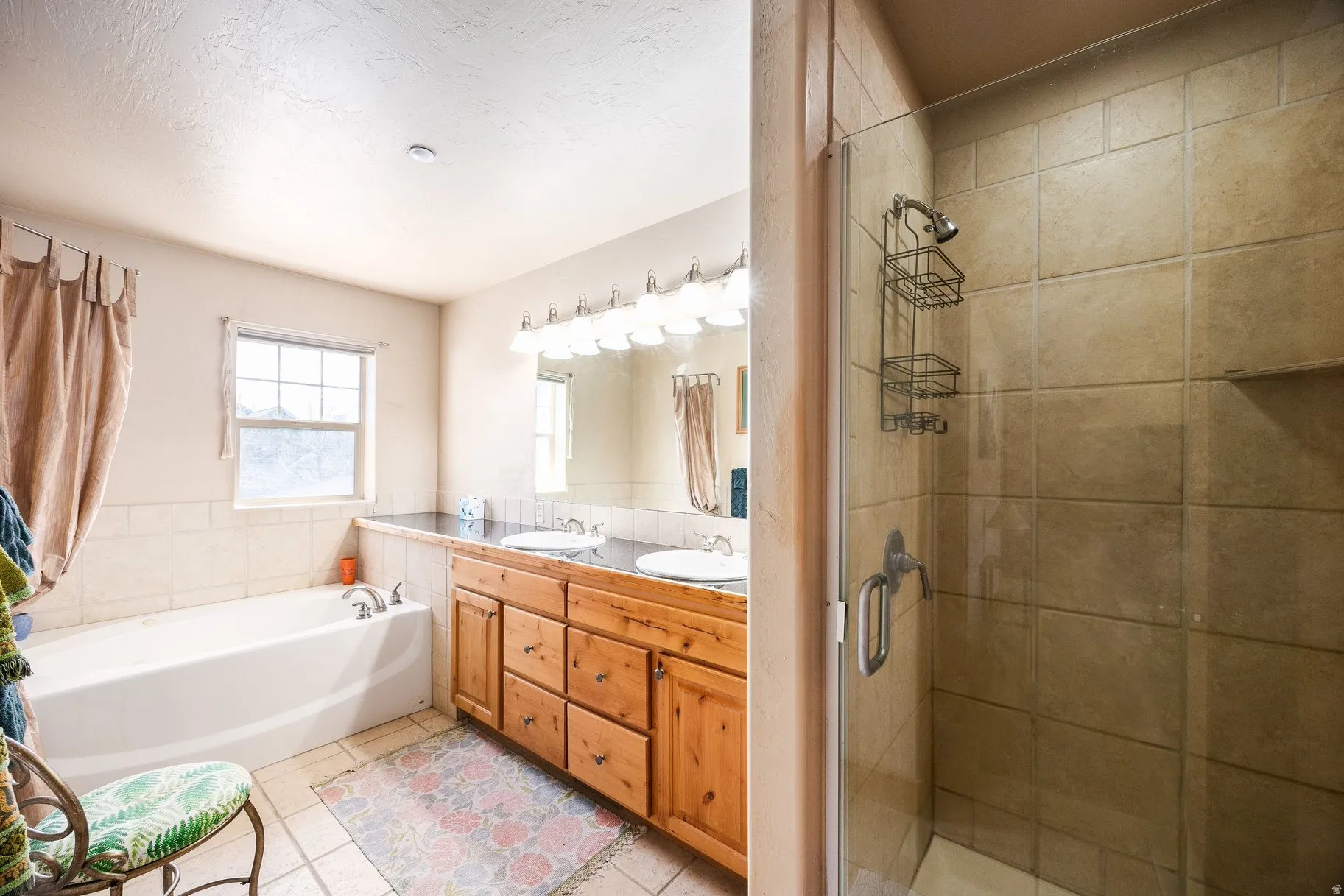 Bathroom featuring a glass-enclosed shower with tiled walls, a separate bathtub, and a wood-finish vanity with dual sinks