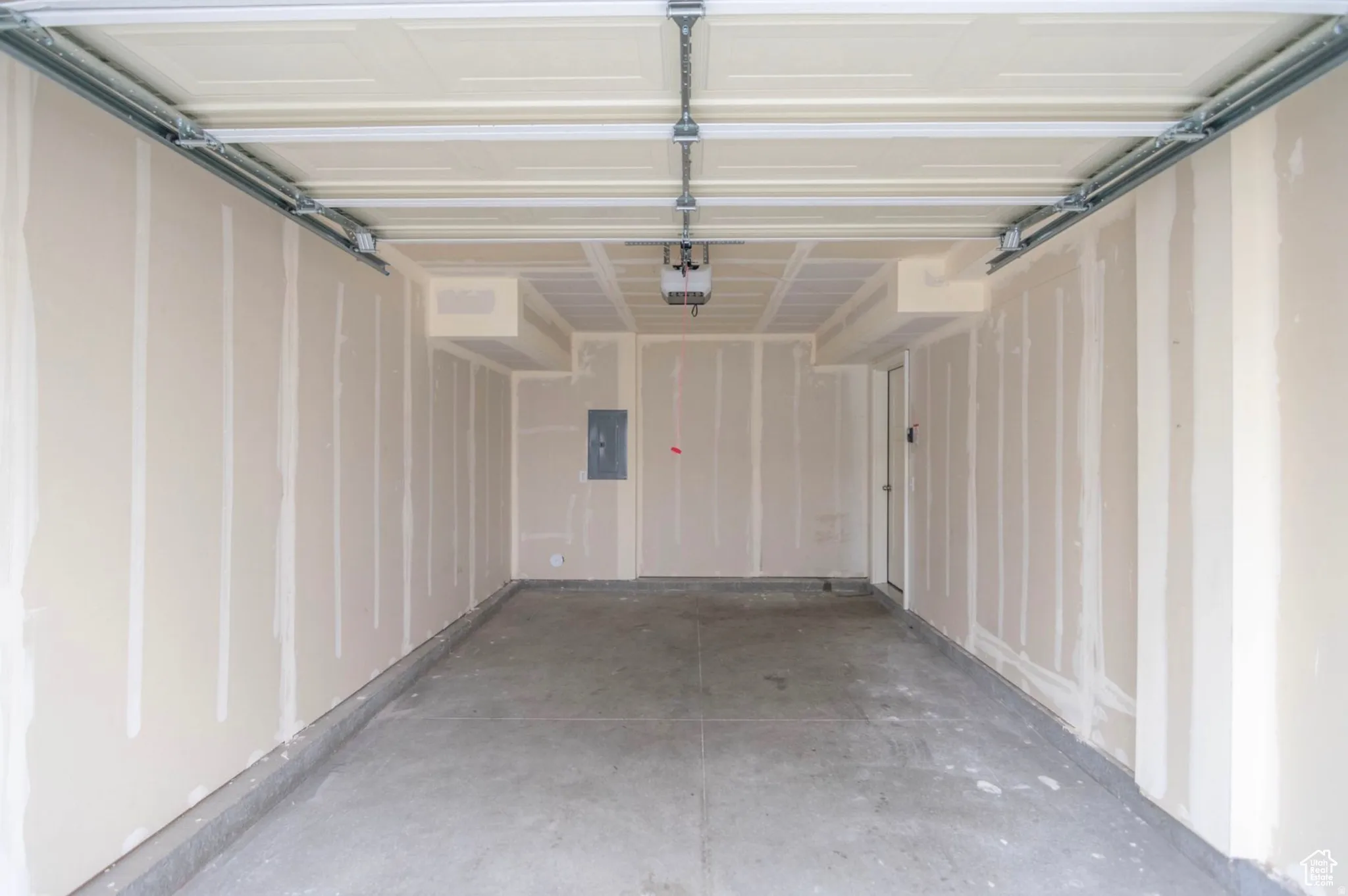 Spacious garage featuring a concrete floor, unpainted drywall walls, and an overhead garage door mechanism