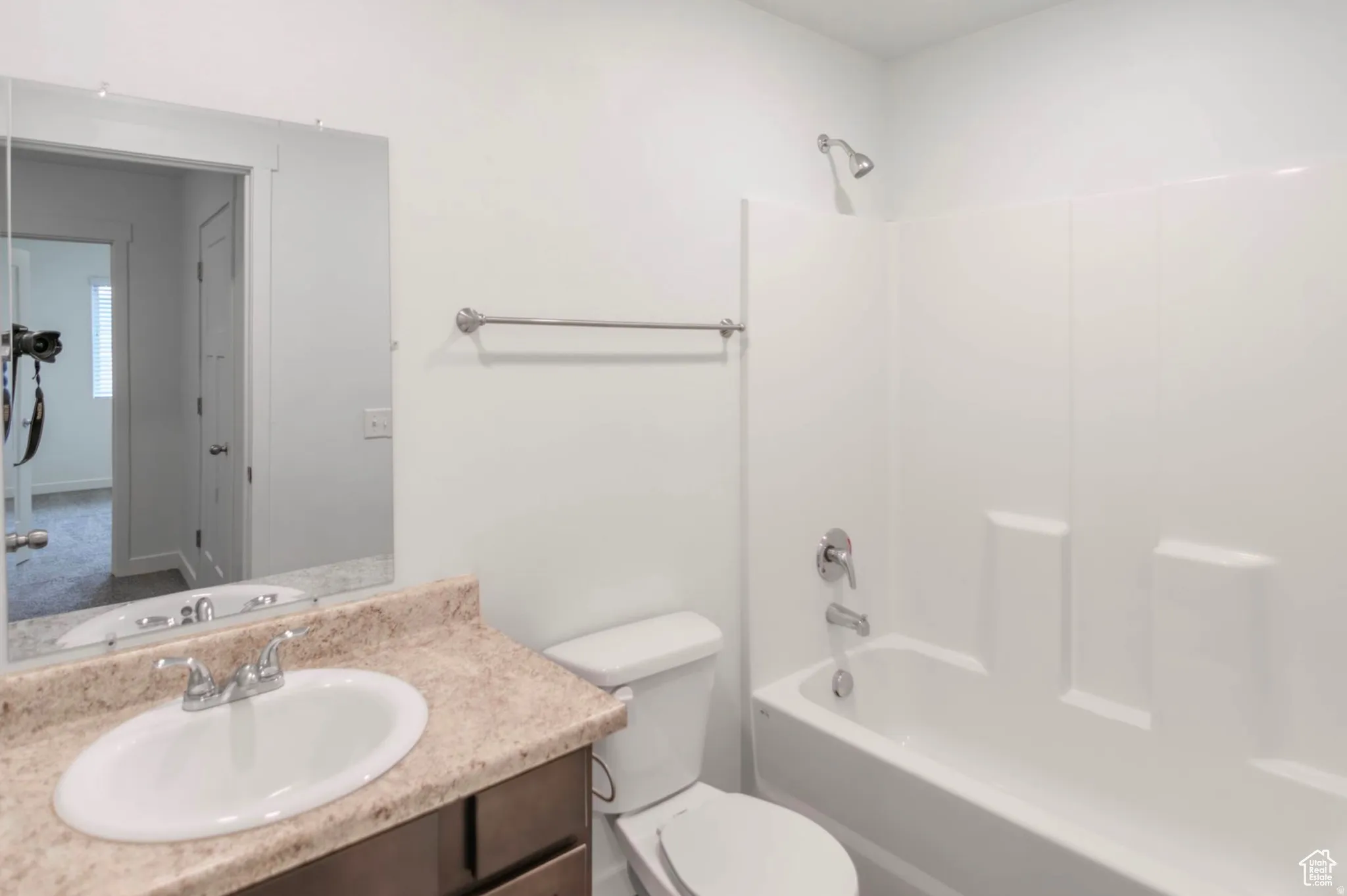 Bathroom featuring a single vanity with a stone-finish countertop, undermount sink, and chrome faucet