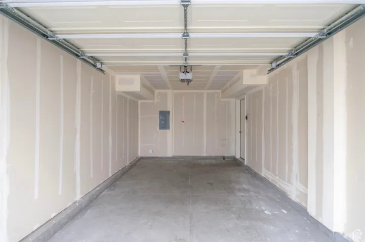 Spacious garage featuring a concrete floor, unpainted drywall walls, and an overhead garage door mechanism