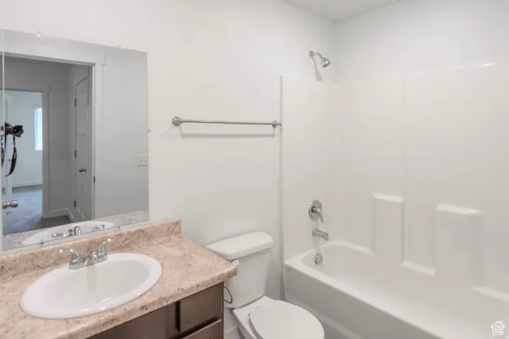 Bathroom featuring a single vanity with a stone-finish countertop, undermount sink, and chrome faucet