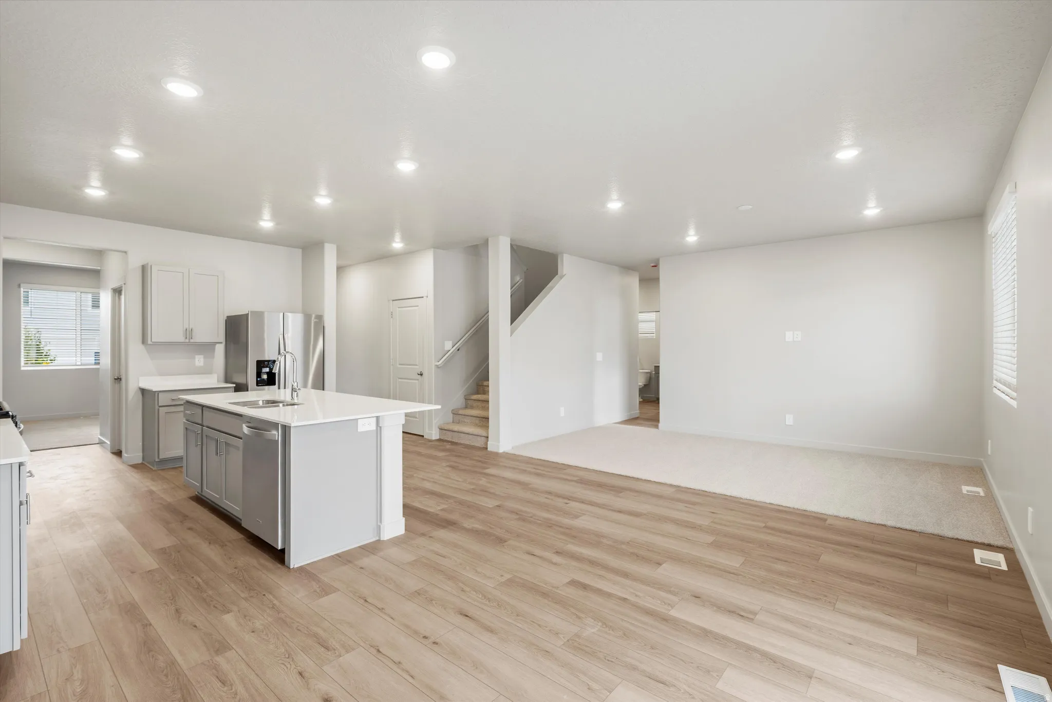 Open-concept living space featuring wood-finish flooring, recessed lighting, and a kitchen island with seating