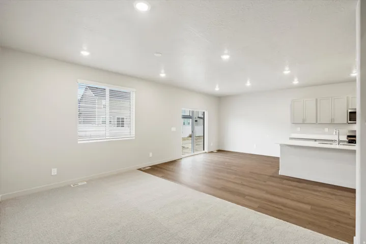 Open-concept living area featuring a kitchen with light-colored cabinetry, a white countertop, and stainless steel appliances