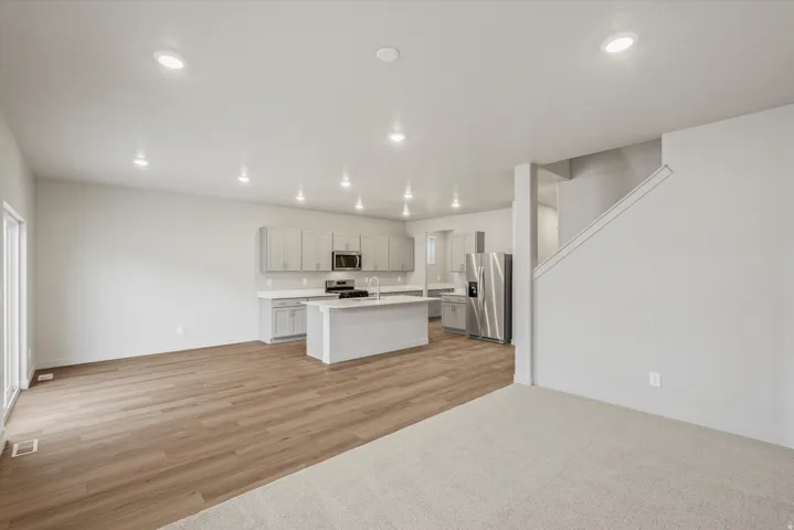 Open-concept living space featuring a modern kitchen with a central island, light cabinetry, and stainless steel appliances