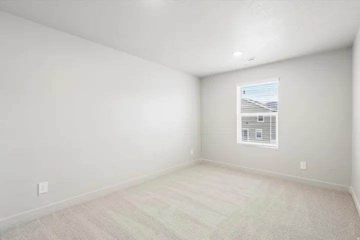 Neutral wall tones with a window offering natural light, paired with plush carpeting and recessed lighting