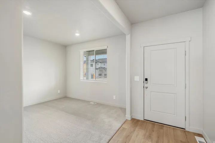 Entryway featuring a paneled door with smart lock hardware, wood-finish flooring, and recessed lighting