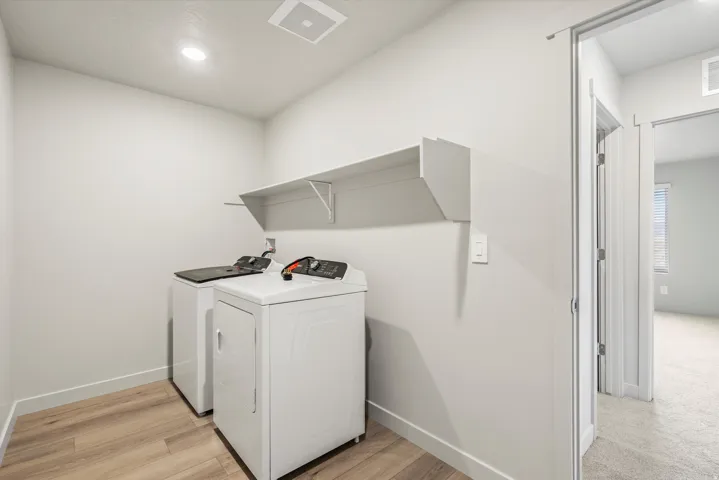 Dedicated laundry area with wood-finish flooring, overhead shelving, and recessed lighting