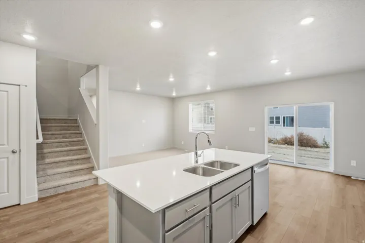 Kitchen island featuring a double-basin sink, chrome faucet, and integrated dishwasher