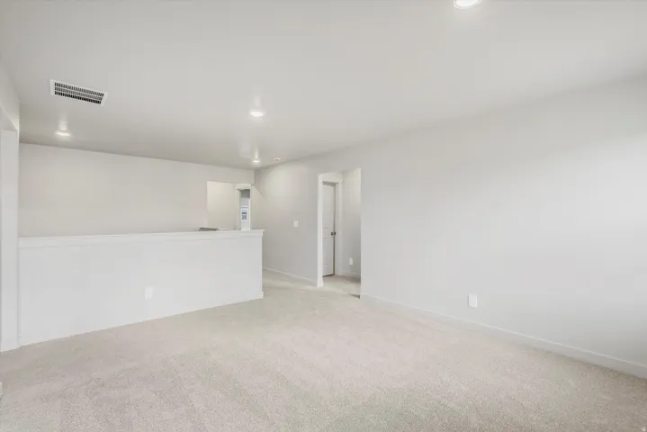 Carpeted upstairs landing featuring a low wall partition, recessed lighting, and a neutral color palette
