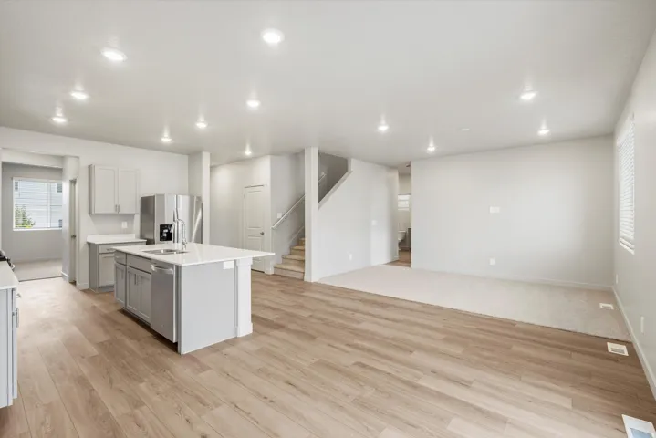 Open-concept living space featuring wood-finish flooring, recessed lighting, and a kitchen island with seating