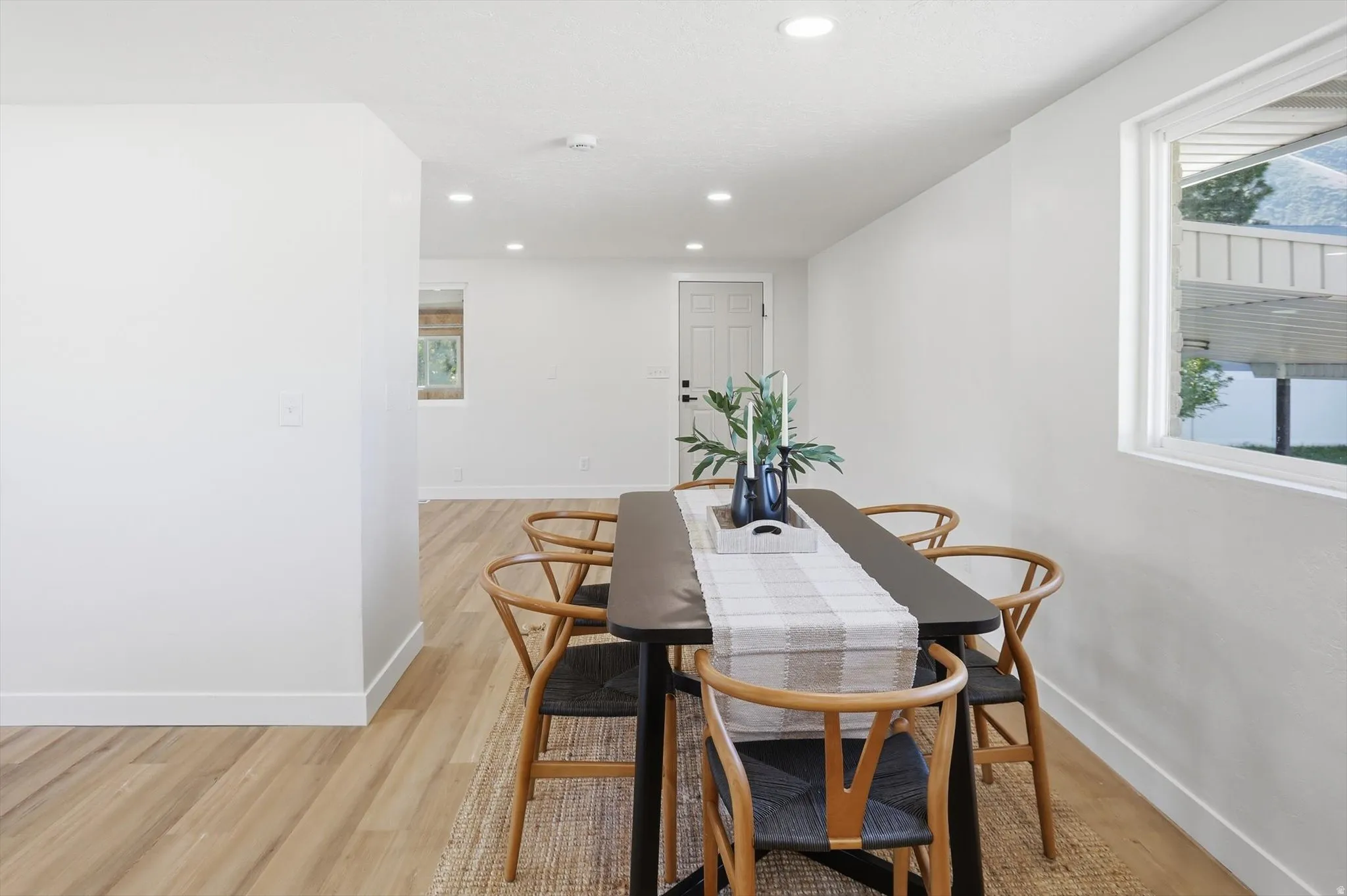 Spacious room with light wood-finish flooring, recessed lighting, and a white interior door