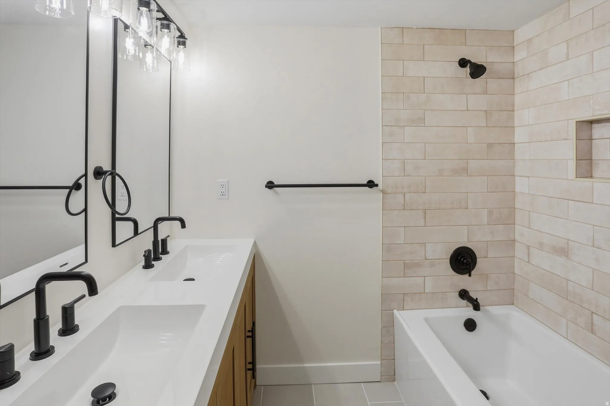 Modern bathroom featuring a dual vanity with integrated sinks, matte black fixtures, and wood-finish cabinetry
