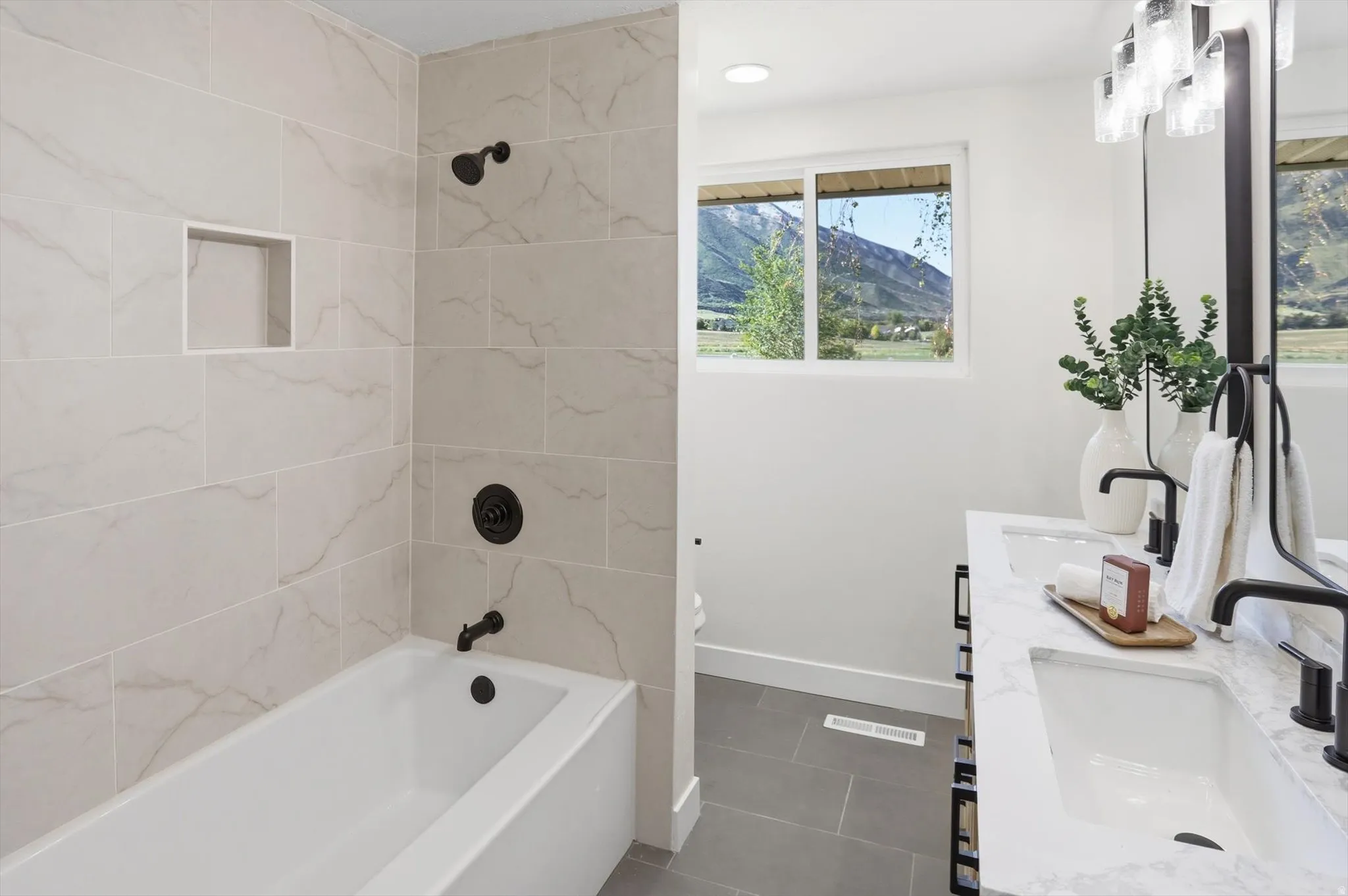 Bathroom featuring a built-in tub with a tiled surround, recessed shower niche, and matte black fixtures