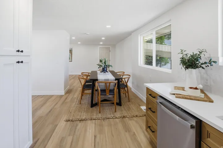 Open-concept dining and kitchen area featuring wood-finish flooring, recessed lighting, and white walls