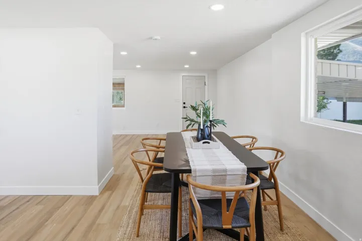 Spacious room with light wood-finish flooring, recessed lighting, and a white interior door