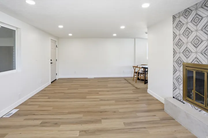 Spacious room featuring wood-finish flooring, recessed lighting, and a window for natural light