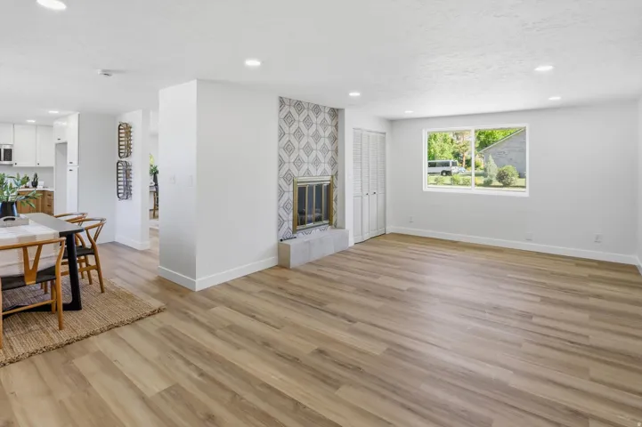 Spacious living area featuring wood-finish flooring, recessed lighting, and a fireplace with a decorative tile surround and stone hearth