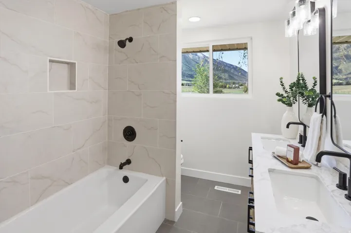 Bathroom featuring a built-in tub with a tiled surround, recessed shower niche, and matte black fixtures