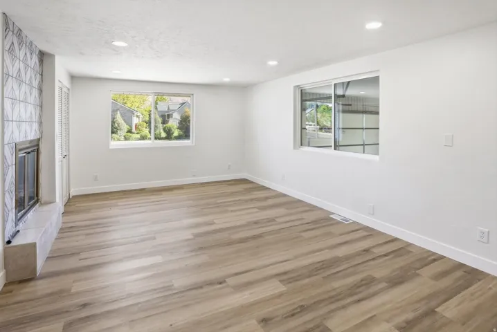 Spacious room featuring wood-finish flooring, recessed lighting, and white baseboards