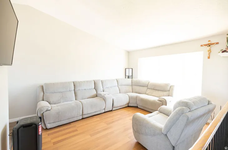 Living space featuring vaulted ceilings, wood-finish flooring, and a large window