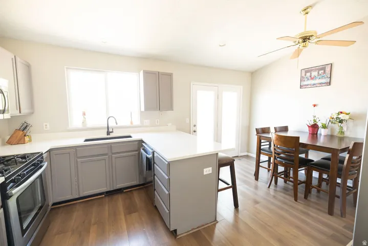 Kitchen and dining area featuring wood-finish flooring, light gray cabinetry, stainless steel appliances, a white countertop, and French doors