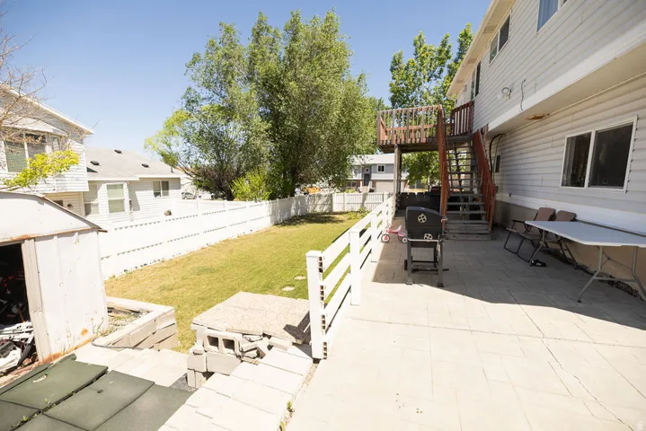 Expansive paved patio with a white picket fence bordering a grass lawn