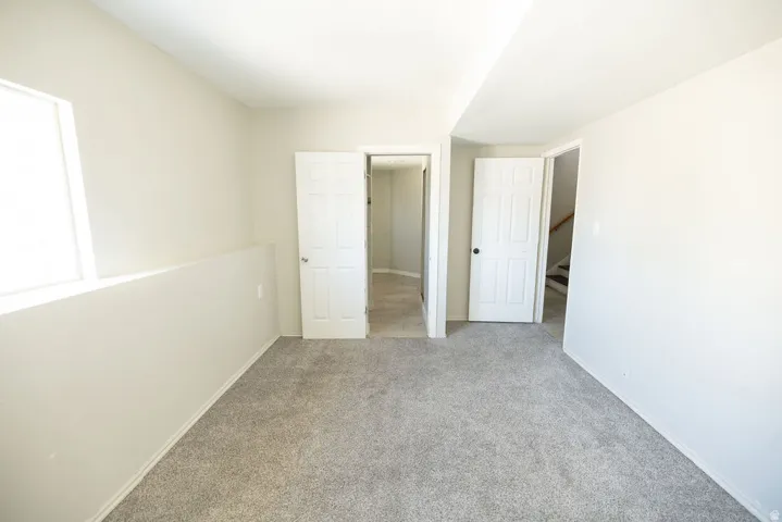 Carpeted interior space with light-toned walls, white trim, and white paneled doors