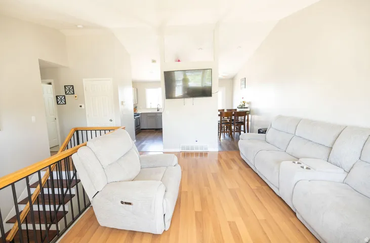 Interior living area featuring wood-finish flooring, light grey walls, and a staircase with a black metal and wood railing