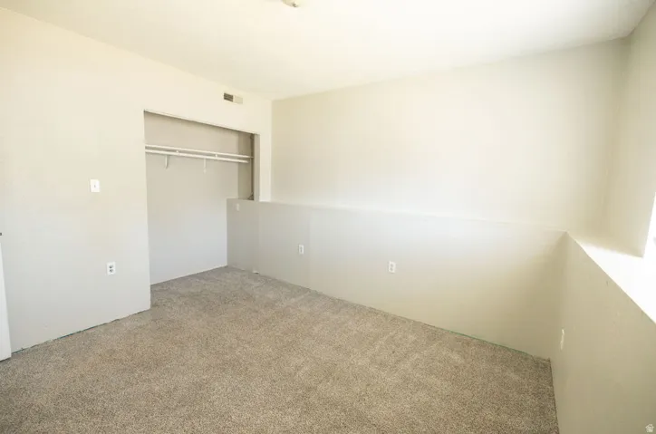 Carpeted room featuring a built-in closet with shelving and hanging rods, a window ledge, and neutral painted walls