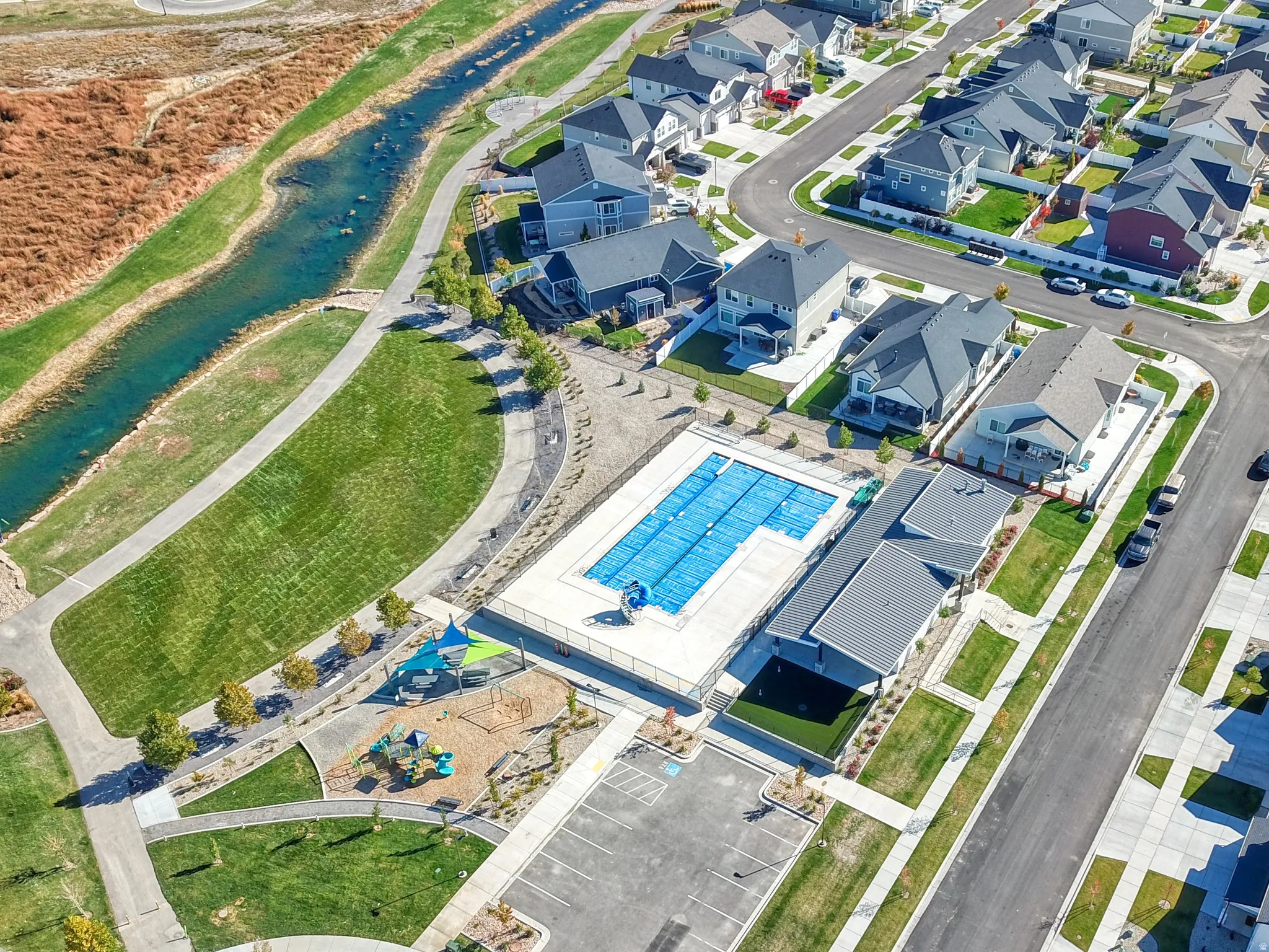 Community amenities featuring a covered swimming pool, adjacent recreational building, and playground