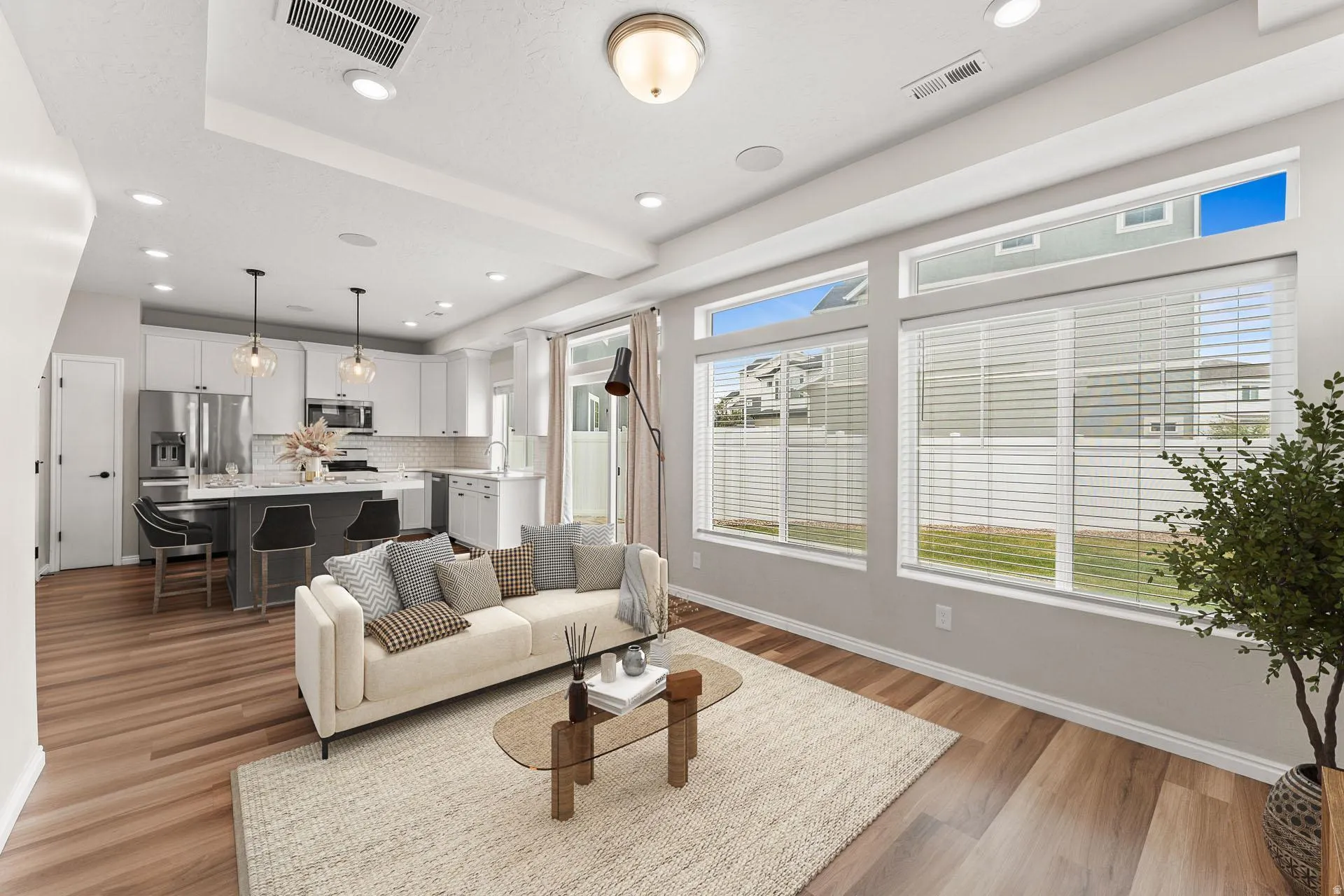 Open-concept living space featuring wood-finish flooring, recessed lighting, and large windows
