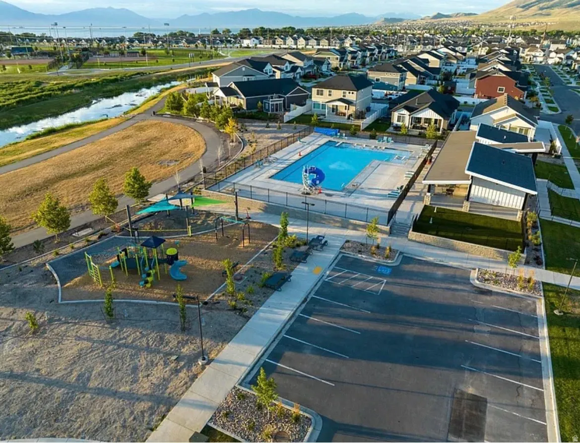 Community amenities featuring a fenced swimming pool, adjacent clubhouse, and a playground with shade structures