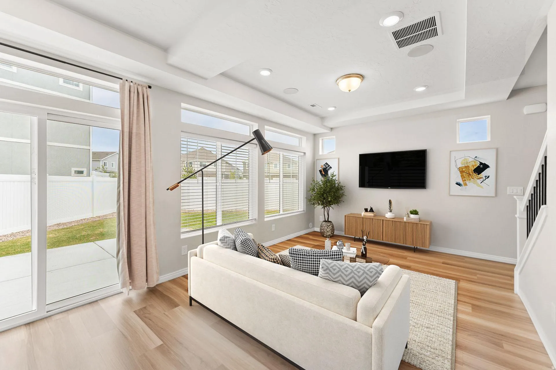 Living area featuring light wood-finish flooring, recessed ceiling lighting, and multiple windows