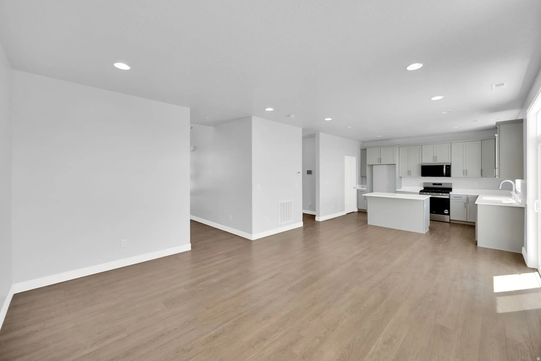 Open-concept living space featuring wood-finish flooring, recessed lighting, and a kitchen with light gray cabinetry