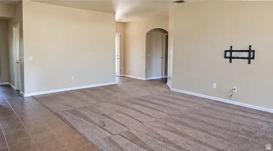 Open concept living space with neutral paint, tile flooring, and carpeted areas