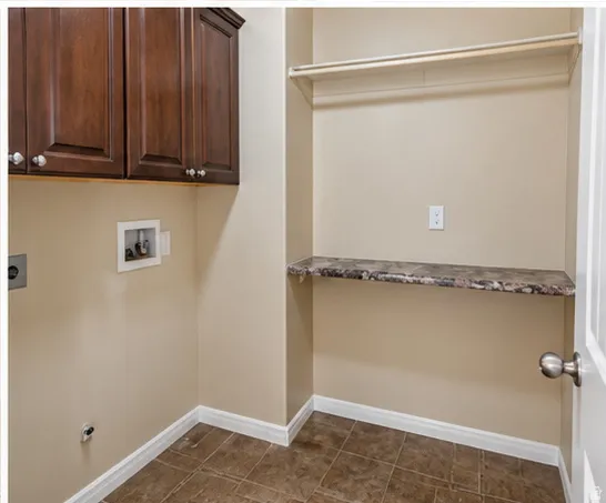 Laundry area featuring rich wood-finish upper cabinetry, a built-in counter, and a clothing rod
