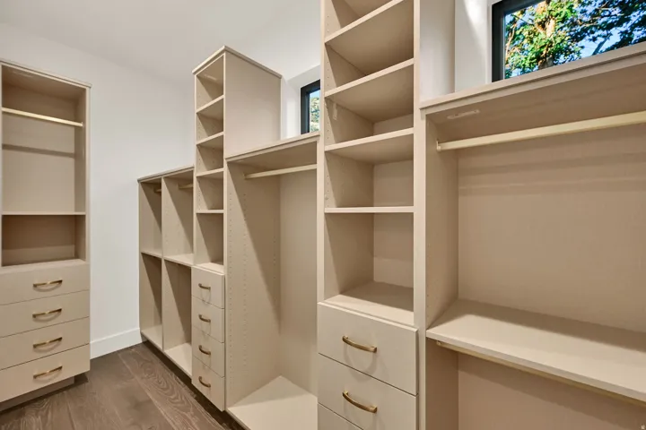 Custom closet system featuring varied shelving, hanging rods, and drawers with curved brass hardware
